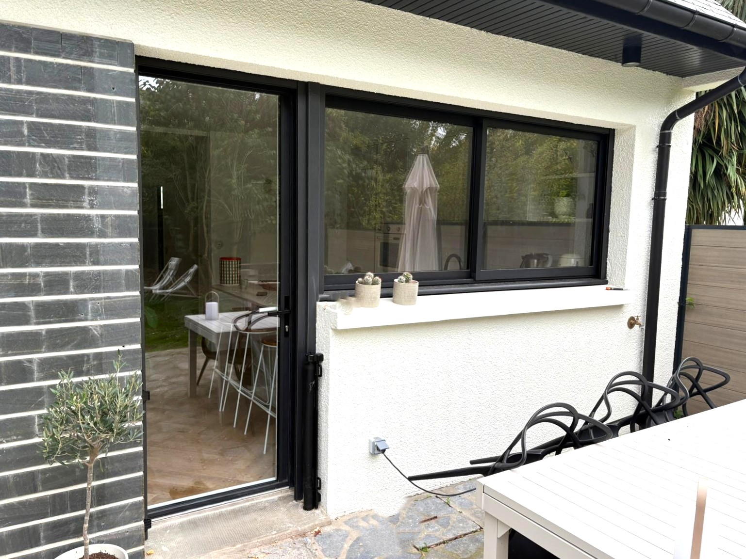 Baie coulissante et fenêtre en aluminium bicolore noir sur une maison rénovée à Pacé, près de Rennes